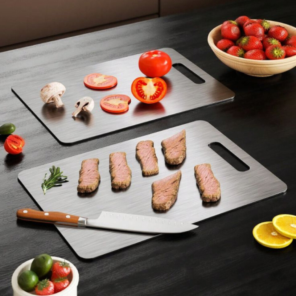 Two Katori titanium cutting boards on a dark counter with sliced tomatoes, mushrooms, steak and a chef's knife